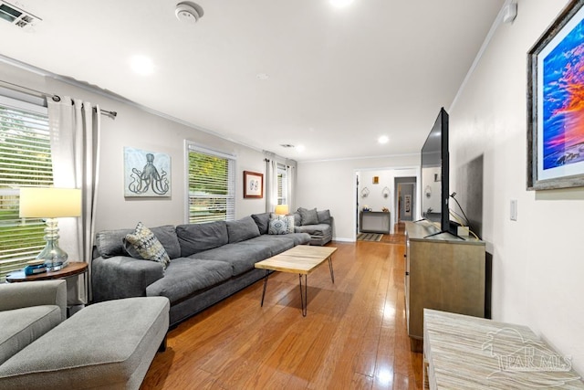 living room with light hardwood / wood-style floors, plenty of natural light, and crown molding