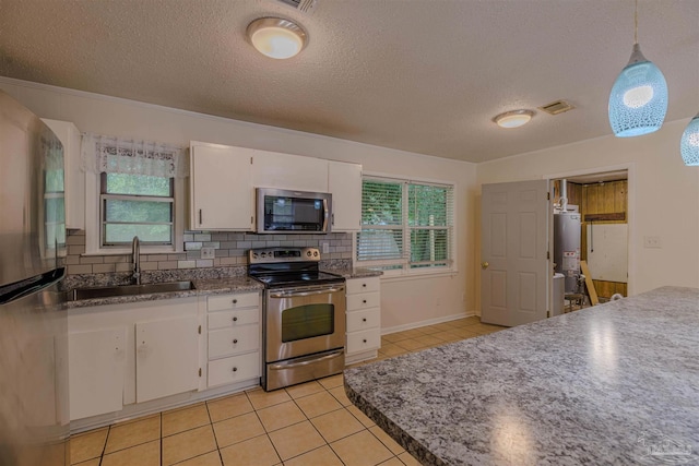 kitchen with white cabinets, gas water heater, tasteful backsplash, decorative light fixtures, and stainless steel appliances