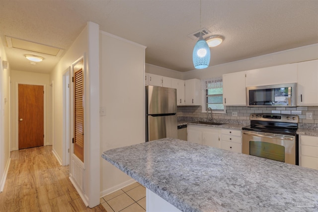 3255 Newton Dr, Pensacola, FL 32503 - kitchen featuring stainless steel appliances, white cabinetry, tasteful backsplash, and a textured ceiling