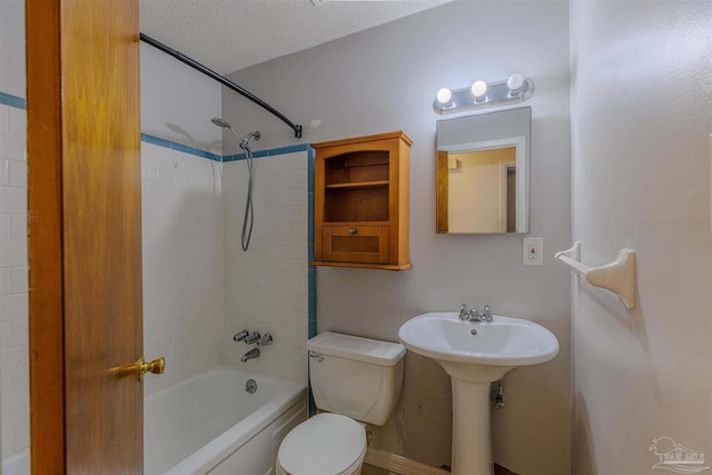 full bathroom featuring a textured ceiling, toilet, tiled shower / bath combo, and sink