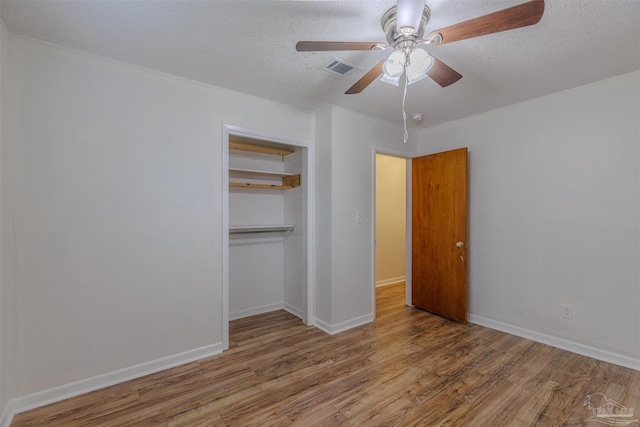 unfurnished bedroom featuring hardwood / wood-style flooring, ceiling fan, a textured ceiling, and a closet