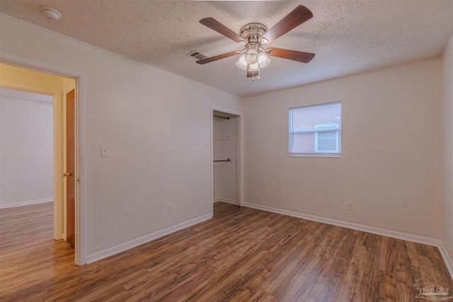 unfurnished bedroom featuring ceiling fan, wood-type flooring, a textured ceiling, and a closet