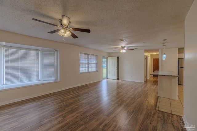 unfurnished living room with ceiling fan, dark hardwood / wood-style flooring, and a textured ceiling