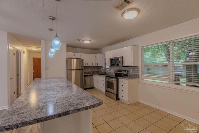 kitchen with sink, hanging light fixtures, tasteful backsplash, white cabinetry, and stainless steel appliances