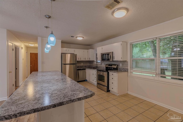 3255 Newton Dr, Pensacola, FL 32503 - kitchen with appliances with stainless steel finishes, a textured ceiling, light tile patterned floors, white cabinets, and decorative backsplash
