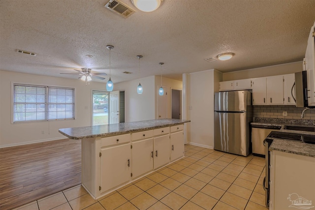 kitchen with white cabinetry, hanging light fixtures, stainless steel appliances, light hardwood / wood-style floors, and a kitchen island