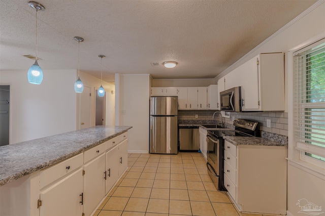 kitchen with a wealth of natural light, pendant lighting, white cabinets, and stainless steel appliances