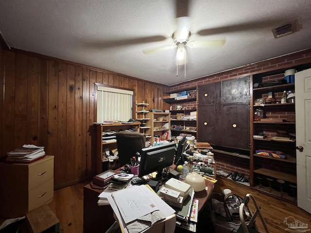 home office with wood walls, ceiling fan, and wood-type flooring