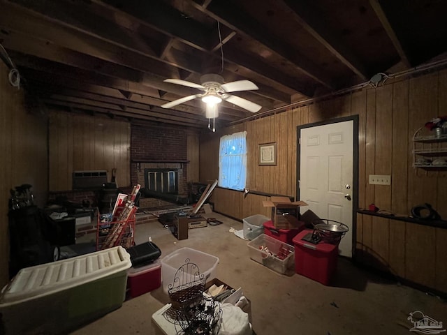 misc room with ceiling fan, wood walls, and a brick fireplace