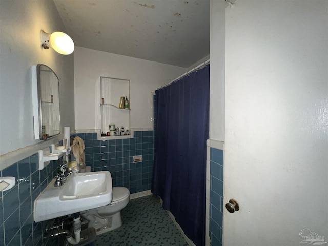 bathroom with walk in shower, toilet, tile walls, and sink