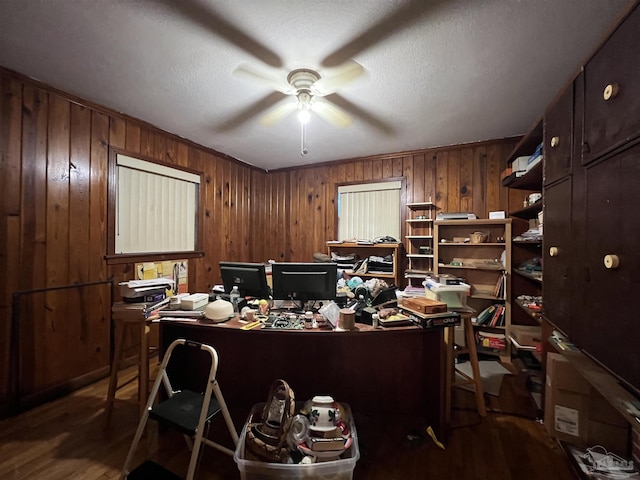 office space featuring a textured ceiling, ceiling fan, wood-type flooring, and wood walls