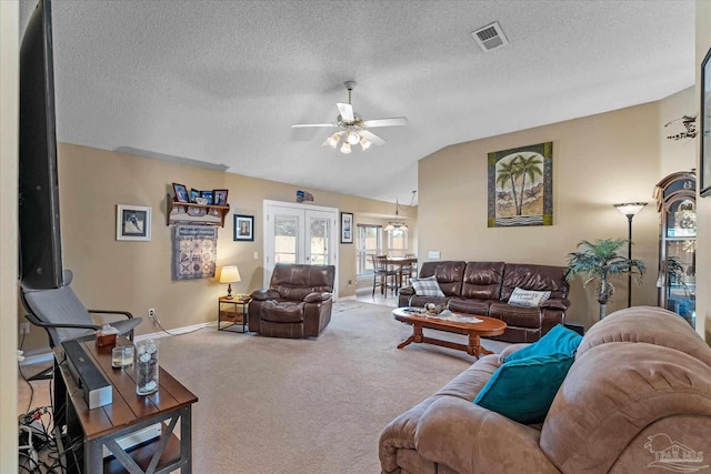 carpeted living room featuring lofted ceiling, ceiling fan, french doors, and a textured ceiling