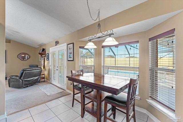 tiled dining area featuring lofted ceiling, a textured ceiling, and french doors