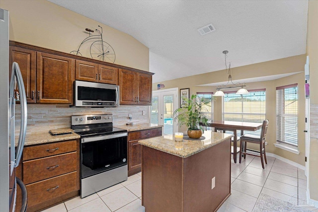 kitchen with a center island, french doors, light stone countertops, tasteful backsplash, and stainless steel appliances