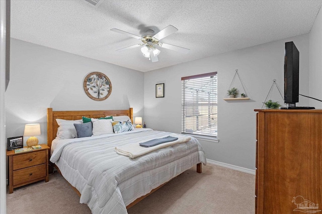 bedroom featuring ceiling fan, light colored carpet, and a textured ceiling