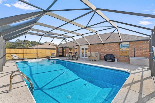 view of pool with glass enclosure, a patio, and french doors