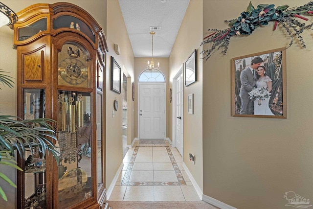 entryway featuring light tile patterned floors, a textured ceiling, and an inviting chandelier