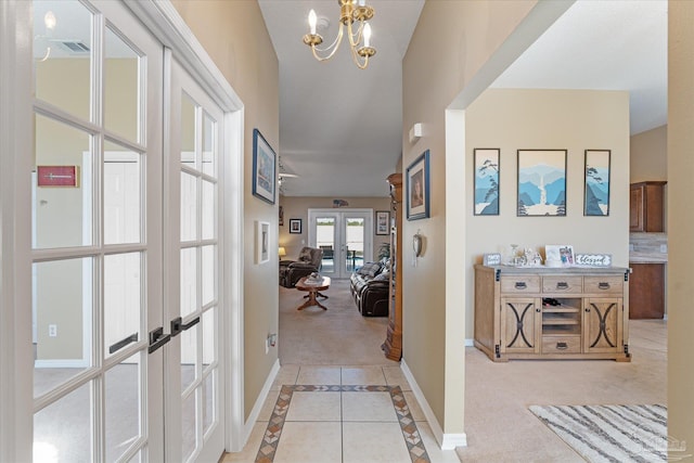 hallway with french doors, light colored carpet, and an inviting chandelier