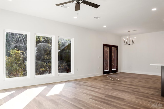 empty room featuring hardwood / wood-style flooring and ceiling fan with notable chandelier