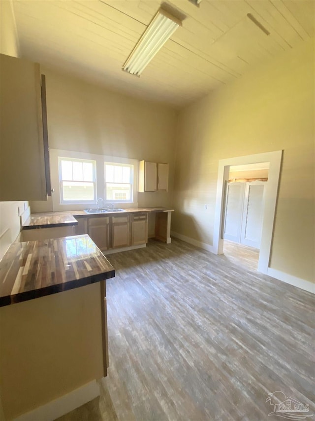 kitchen featuring wood counters, sink, light hardwood / wood-style flooring, and wooden ceiling