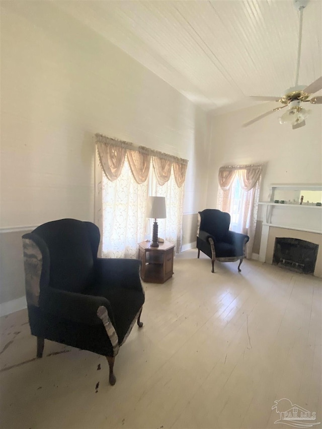 sitting room with ceiling fan and wood-type flooring