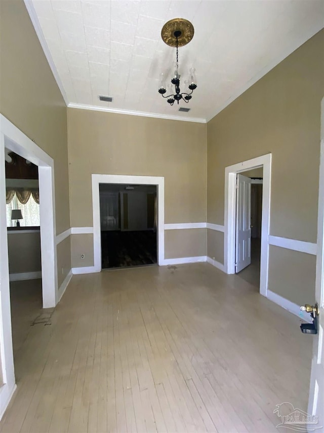 unfurnished living room with wood-type flooring, ornamental molding, and a chandelier