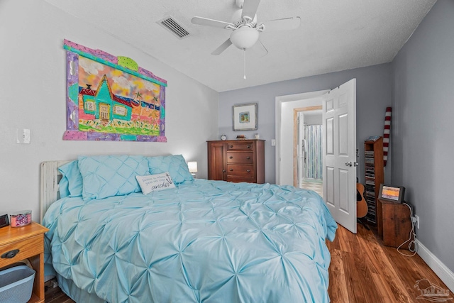 bedroom featuring visible vents, ceiling fan, baseboards, and wood finished floors