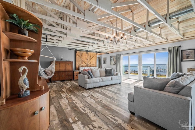 living room featuring wood finished floors, a notable chandelier, and a barn door