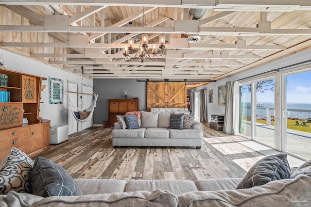 living room with vaulted ceiling, a barn door, wood finished floors, and a chandelier