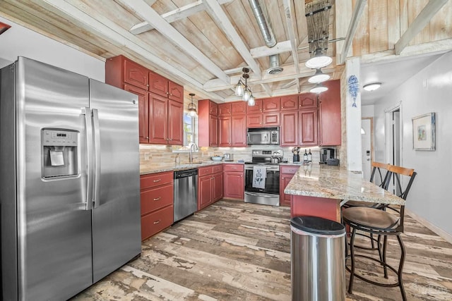 kitchen with light wood-style flooring, stainless steel appliances, a peninsula, a sink, and tasteful backsplash