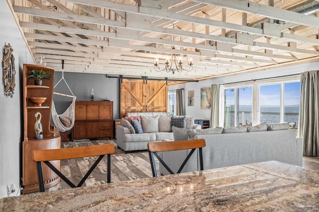 living room with a water view, a barn door, and wood finished floors