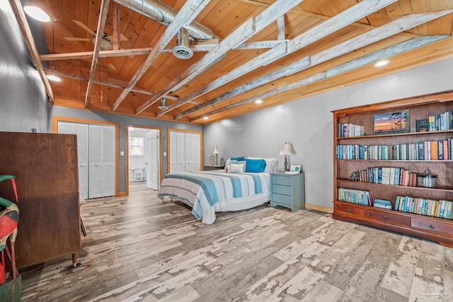 bedroom with multiple closets, visible vents, baseboards, and wood finished floors