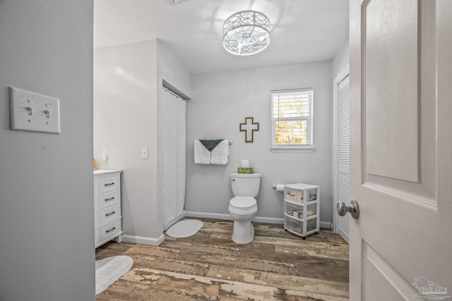 full bathroom with baseboards, a shower with shower curtain, toilet, wood finished floors, and vanity