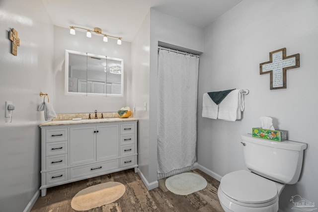 bathroom featuring toilet, a shower with shower curtain, wood finished floors, vanity, and baseboards