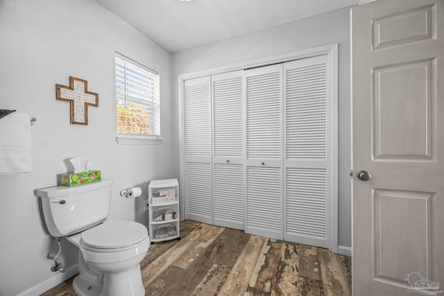 bathroom featuring a closet, wood finished floors, toilet, and baseboards