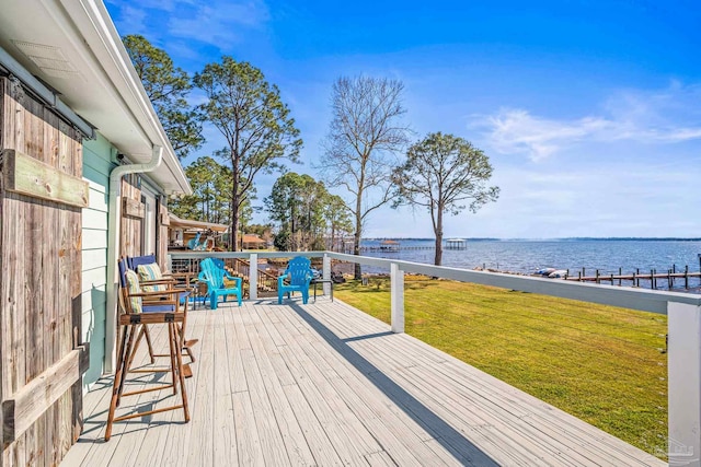 wooden terrace featuring a water view and a lawn