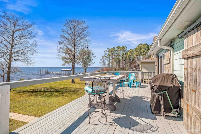 wooden terrace with a water view, a grill, and a yard