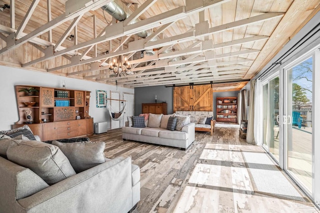 living area featuring vaulted ceiling, a barn door, wood finished floors, and a notable chandelier