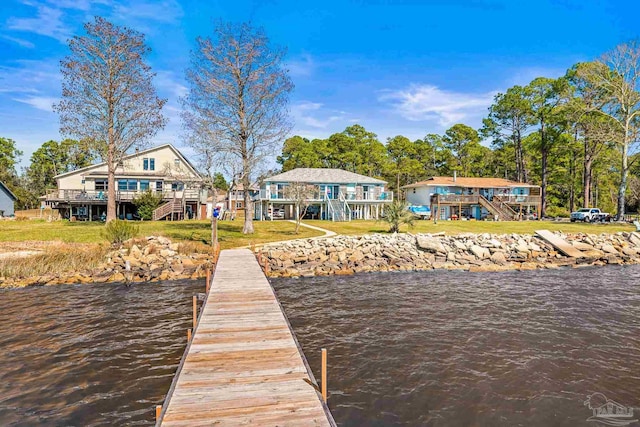 dock area featuring a water view, a lawn, and stairway