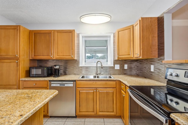 kitchen featuring light stone counters, sink, light tile patterned floors, and stainless steel appliances