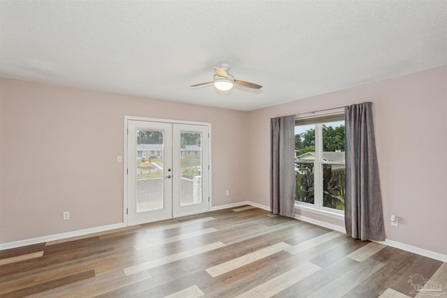 unfurnished room featuring ceiling fan, french doors, a textured ceiling, and light wood-type flooring