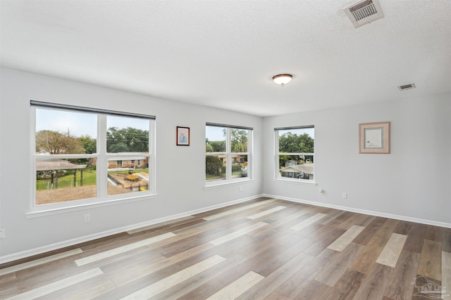 empty room featuring a textured ceiling and light hardwood / wood-style flooring