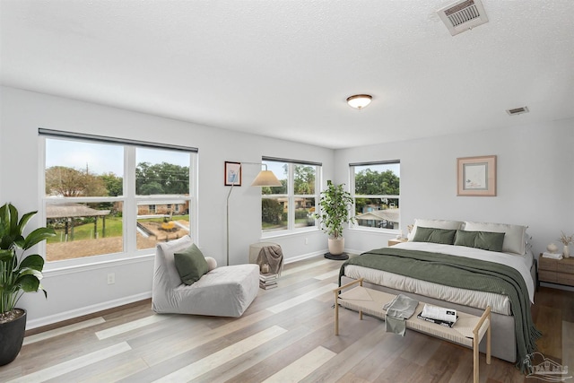 bedroom with light hardwood / wood-style flooring and a textured ceiling