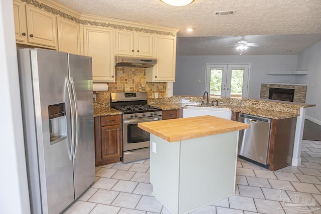 kitchen featuring visible vents, a peninsula, ceiling fan, a sink, and appliances with stainless steel finishes
