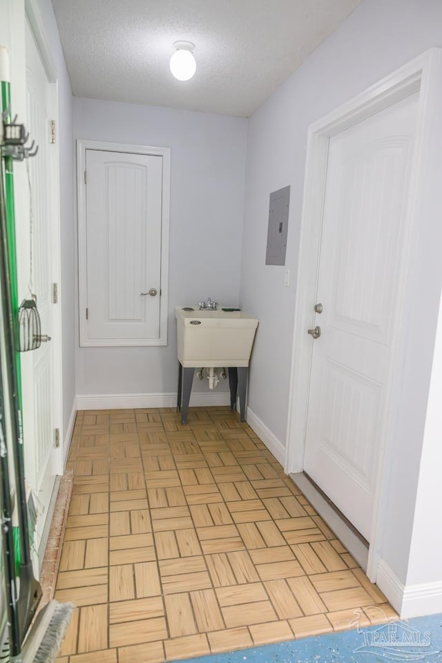 interior space featuring baseboards, a textured ceiling, and electric panel