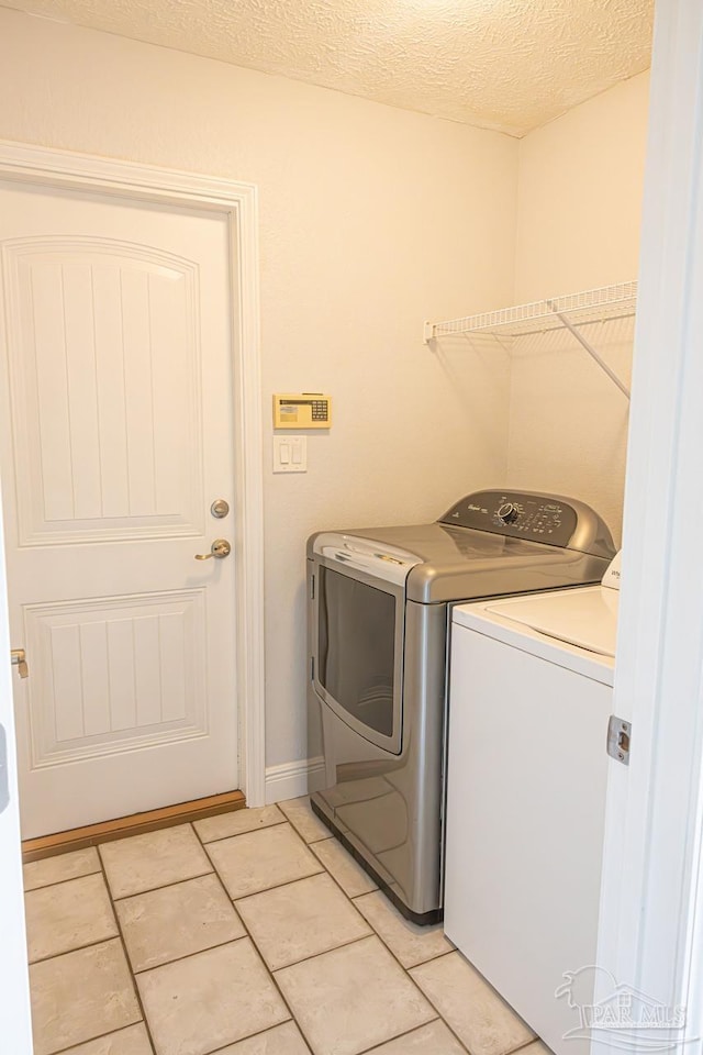 laundry area with separate washer and dryer, laundry area, light tile patterned floors, and a textured ceiling