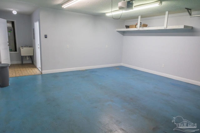 garage featuring baseboards, a sink, and a garage door opener