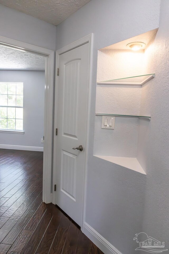 interior space featuring a textured ceiling, baseboards, and wood finished floors