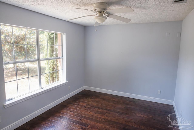spare room featuring a textured ceiling, a ceiling fan, baseboards, dark wood-type flooring, and visible vents