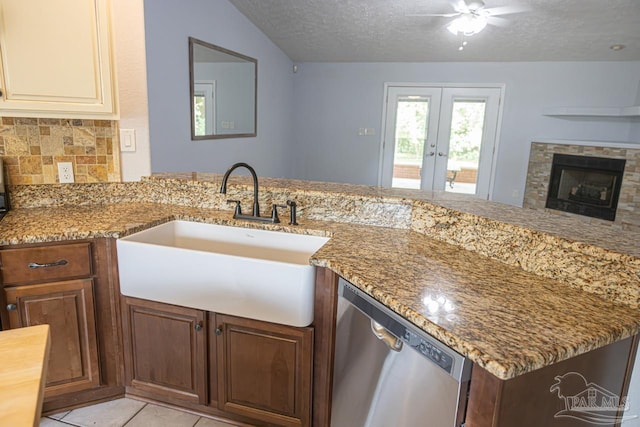 kitchen featuring stainless steel dishwasher, light stone countertops, a textured ceiling, french doors, and a sink